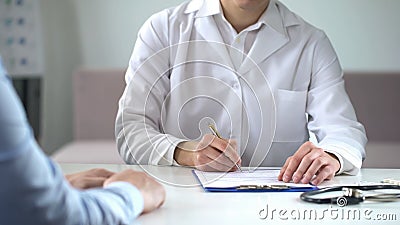 Therapist writing down patient complaint in medical form, consultation in clinic Stock Photo