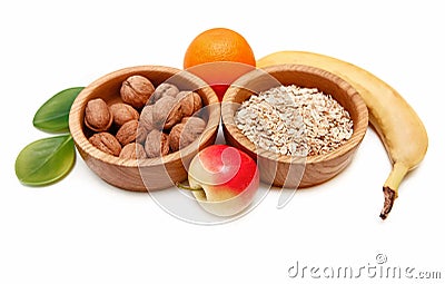 There are Banana,Apple,Orange with Walnuts in the Wooden Plate and Rolled Oats,with Green Leaves,Healthy Fresh Organic Food on the Stock Photo