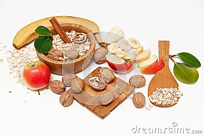 There are Banana,Apple,Walnuts in the Wooden Plate and Rolled Oats,Wooden Spoon,Trivet,with Green Leaves,Healthy Fresh Organic Foo Stock Photo