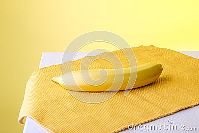 There is a banana on the napkin, the background is yellow Stock Photo