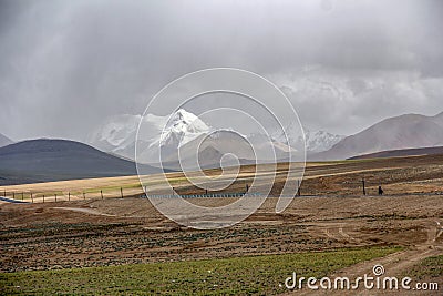 There is a beautiful and spectacular snow mountain in the distance of the dark clouded sky Stock Photo