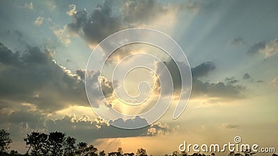 There is a beautiful sunset, light yellow light is spread all around and brown color cloud hidden the light of sun. Kushinagar Stock Photo