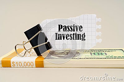 There are dollars on the table, on which there is a clip and torn paper with the inscription - Passive Investing Stock Photo