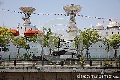 There is a huge oceangoing survey ship docked by the river. Next to the ship is an abandoned wharf, with abandoned transport vehic Stock Photo