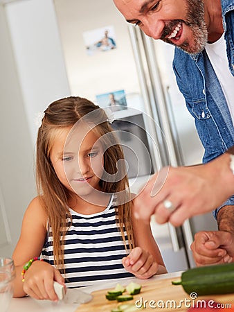 There are many ways to nurture your kids. an adorable little girl cooking with her father at home. Stock Photo