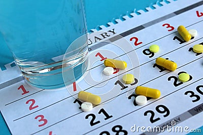 There is medicine on the calendar every day and there is a glass of water Stock Photo