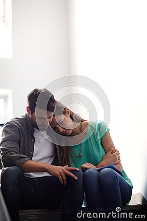 There when she needs a shoulder to cry on. a man comforting a distressed woman in a stairwell. Stock Photo
