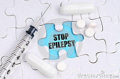 There are pills and a syringe on the white puzzles. Inside on a blue background the inscription - STOP EPILEPSY Stock Photo