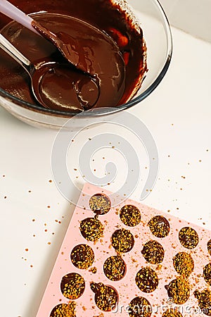 There is a silicone mold filled with chocolate mixture on the table. Making chocolates Stock Photo