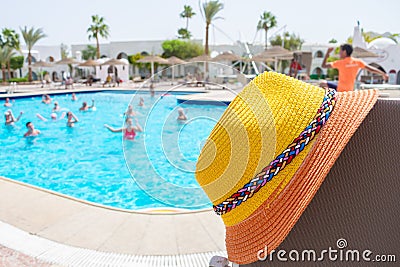 There is a tourist hat at the pool where the party takes place. A beach hat is on the background of a pool with people Stock Photo