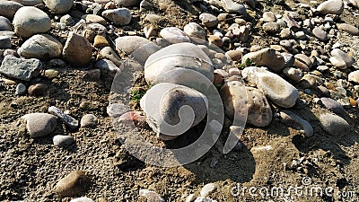There are two stones one behind the other and so many pebbles around there Stock Photo