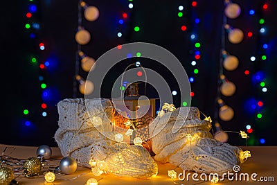 There are wool white socks like foots, lights and candle stick behind the socks on the table/background. Stock Photo
