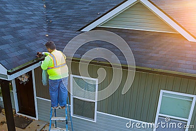 There is a worker cleaning clogged roof gutter drain which has been clogged with dirt, debris, fallen leaves. Stock Photo