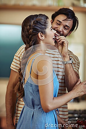Theres no love sincerer than the love of food. an affectionate young couple snacking while preparing a meal in their Stock Photo