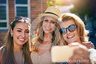 Theres always time for a selfie. three young girlfriends taking selfies while outdoors. Stock Photo