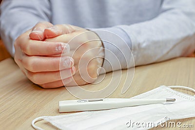 Thermometer and face mask on a table Stock Photo