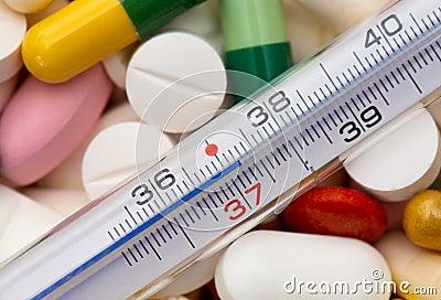 Thermometer indicating a temperature of 37 Â°C. Background of tablets, capsules and pills of different kinds and colors Stock Photo