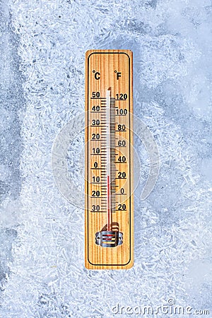 Thermometer laying on ice, showing minus 5 degrees. Sun shining from side. Winter / low temperatures coming, concept Stock Photo