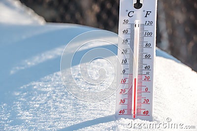 The thermometer lies on the snow and shows a negative temperature in cold weather on the blue sky.Meteorological conditions with Stock Photo