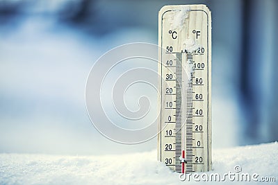 Thermometer on snow shows low temperatures under zero. Low temperatures in degrees Celsius and fahrenheit. Stock Photo