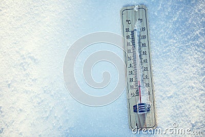 Thermometer on snow shows low temperatures under zero. Low temperatures in degrees Celsius and fahrenheit. Stock Photo