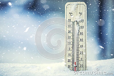 Thermometer on snow shows low temperatures under zero. Low temperatures in degrees Celsius and fahrenheit. Stock Photo