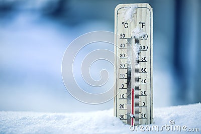 Thermometer on snow shows low temperatures - zero. Low temperatures in degrees Celsius and fahrenheit. Cold winter weather - zero. Stock Photo