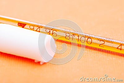 Thermometer and suppository medication on orange. Rectal drug administration. Stock Photo