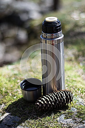 Thermos, cup and pinecone- picnic on mossy rock Stock Photo