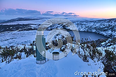 Thermos and a cup of tea at the snowy summit and scenic evening view over Lough Bray Upper lake seen from Eagles Crag Stock Photo