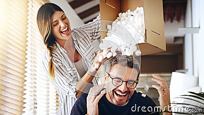 Theyre just being silly. a mature couple having fun with foam packaging balls while moving house. Stock Photo