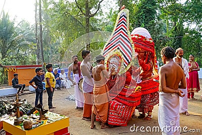 A Theyyam artist is adorned with traditional colorful costume and a mask before a performance at the festival in Kannur, Kerala Editorial Stock Photo