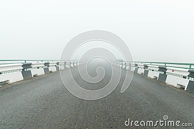 Thick fog and an asphalt road with a fence. Hazardous weather conditions for the driver Stock Photo