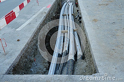 Thick polypropylene pipes in a building pit on a street of civil engineering building site with barrier planks in red and white Stock Photo