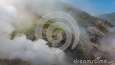 Thick steam from an erupting geyser swirls over the hillsides. Stock Photo