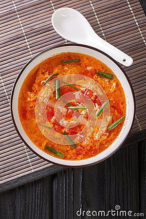 Thick tomato egg drops soup or Chinese flower soup close-up in a bowl. Vertical top view Stock Photo