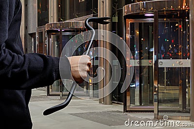 Thief with a burglar tool in his hands at the entrance of the store door Stock Photo