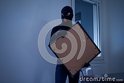 Thief inside home stealing a painting Stock Photo