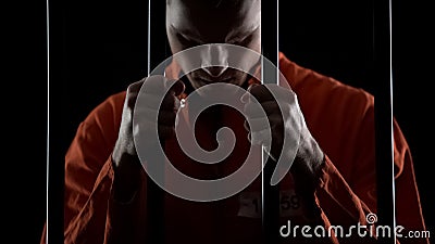 Thief in jail feeling sincere regret of crime, holding prison bars in desperate Stock Photo