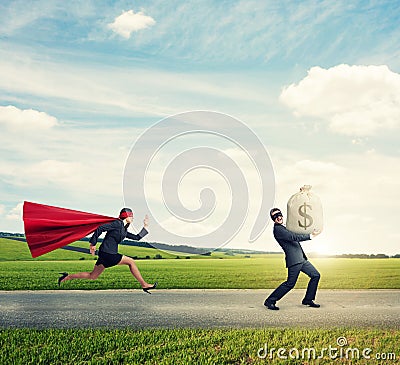 Thief running away from superwoman Stock Photo
