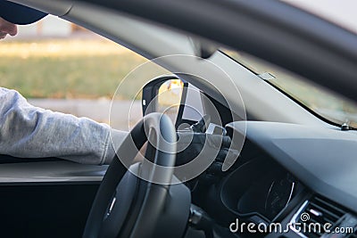 The thief`s hand in a black glove, takes the smartphone from the front of the car, through the open glass Stock Photo