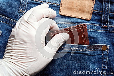 Thief wears a white vinyl glove steal a wallet from the back pocket of jeans. Close up view of pick pocketing Stock Photo