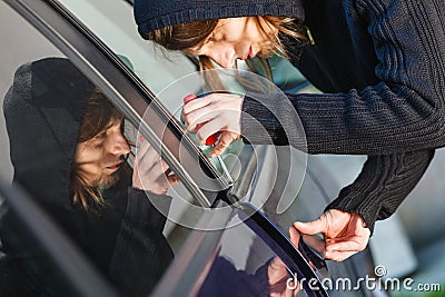 Thieft man holding screwdriver breaking into car Stock Photo