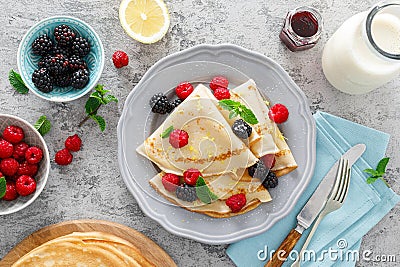 Thin crepes with fresh berries and lemon zest. Pancakes with raspberry and blackberry Stock Photo