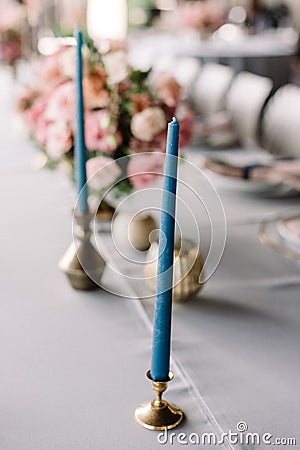 A thin elegant blue candle in a stylish metal candlestick in wedding decor Stock Photo