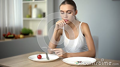 Thin girl looking at anti-obesity pills, obsession with weight loss, addiction Stock Photo