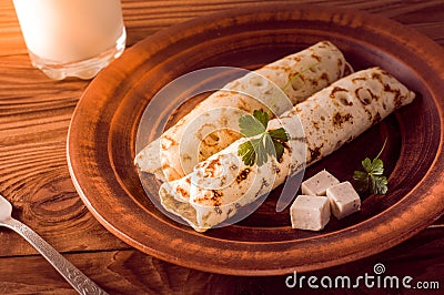 Thin pancakes with filling and slices of cheese with herbs. Morning rays of the sun. Breakfast Stock Photo