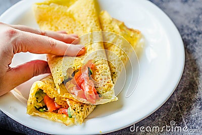 Thin pancakes with red fish on plate, top view.Crepes with filet salmon and cheese, red fish and green avocado on white plate over Stock Photo