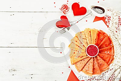 Thin red crepes or pancakes with raspberry sugar and sweet hearts pastry topping Stock Photo