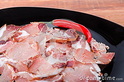 Thin slices of dried pork neck on black dish closeup Stock Photo